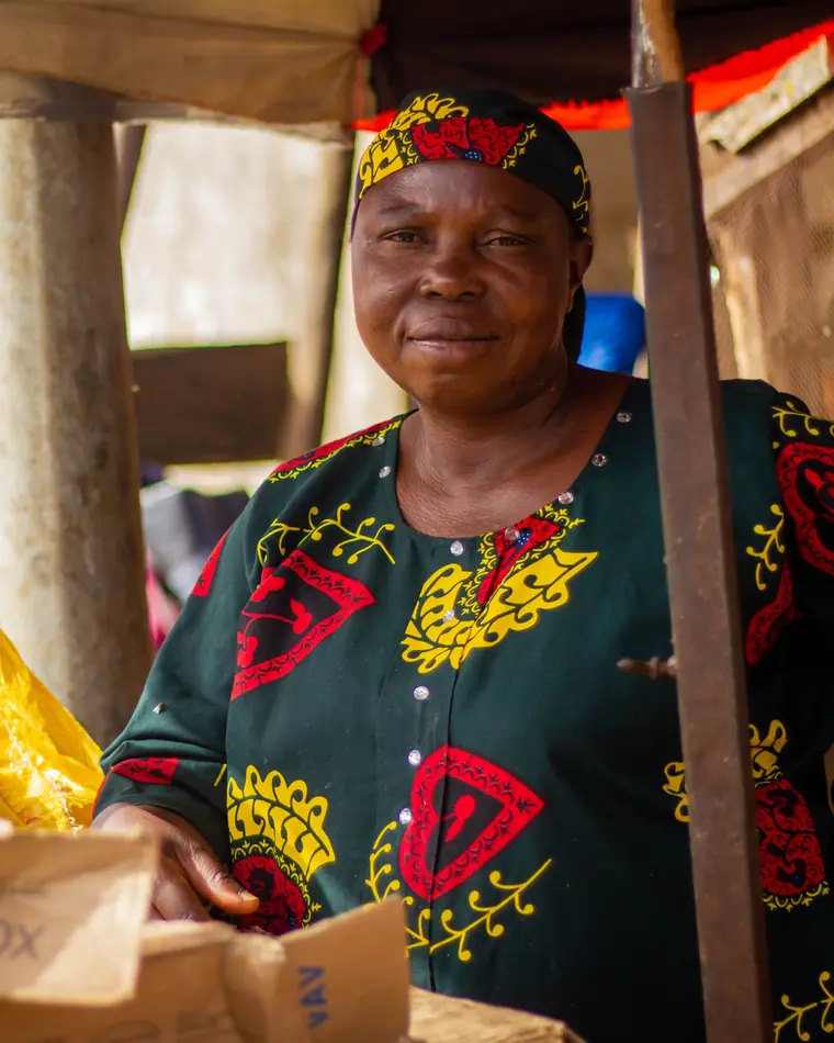 Une vendeuse sourit derrière son étal, au marché, à côté d’une balance.
